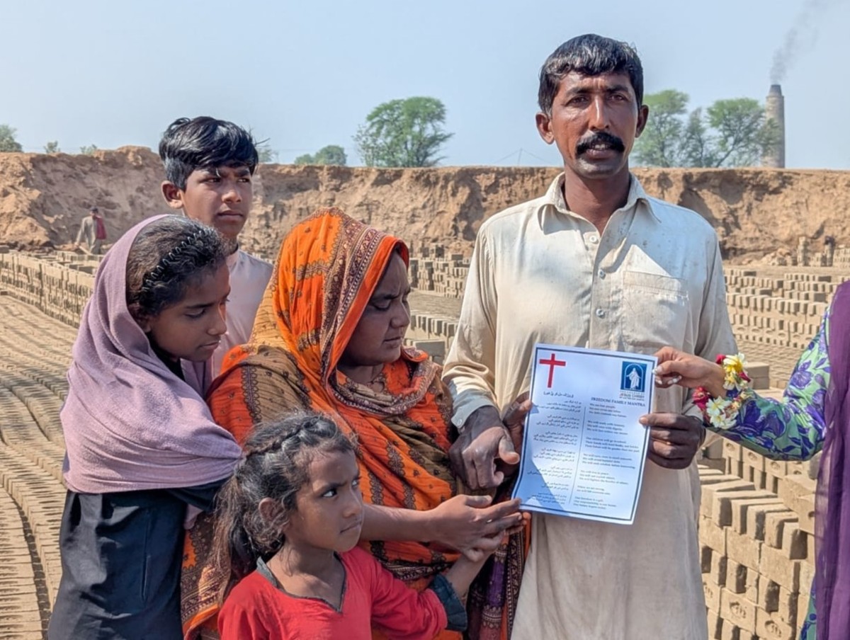 Akbar Dukhi and his family at the brick kiln, receiving a Freedom Family document from the TLUCF team