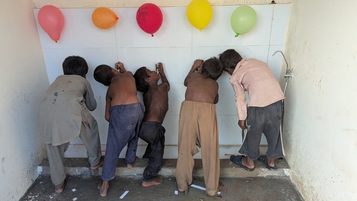 Boys washing up at a row of sinks decorated with balloons