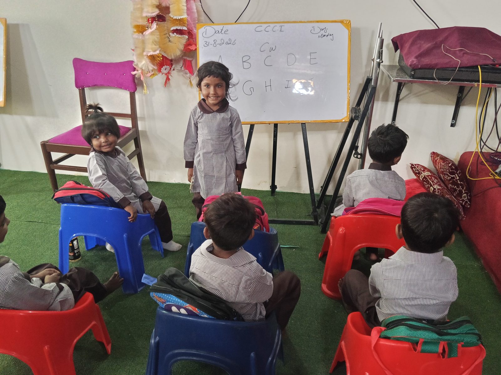 Students standing beside a whiteboard with the alphabet during circle time