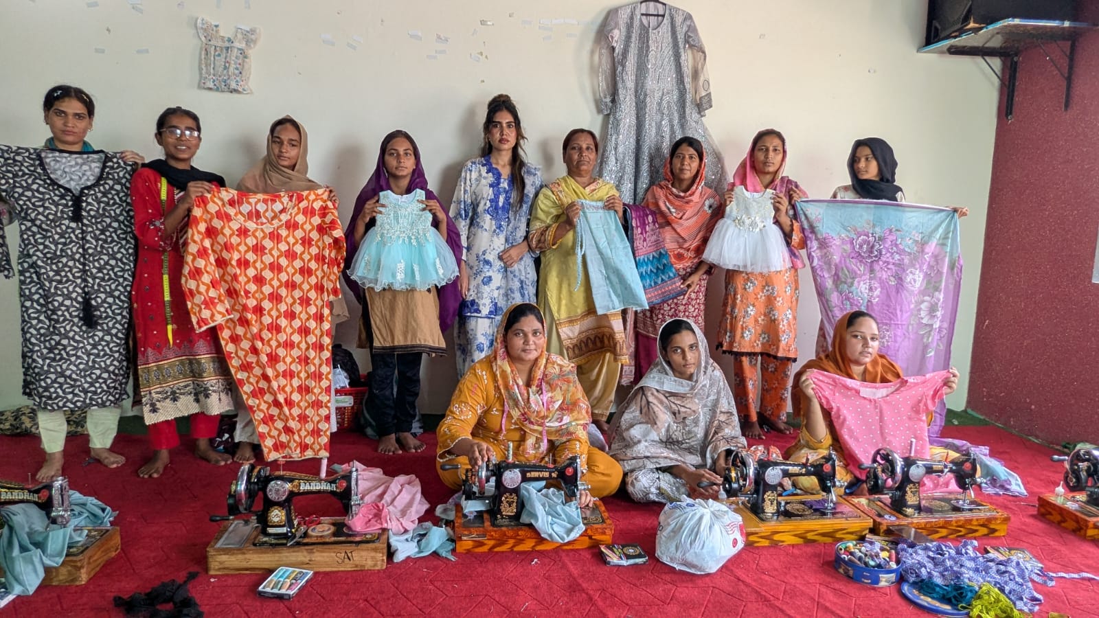 Sewing ministry students and graduates holding up the garments they made