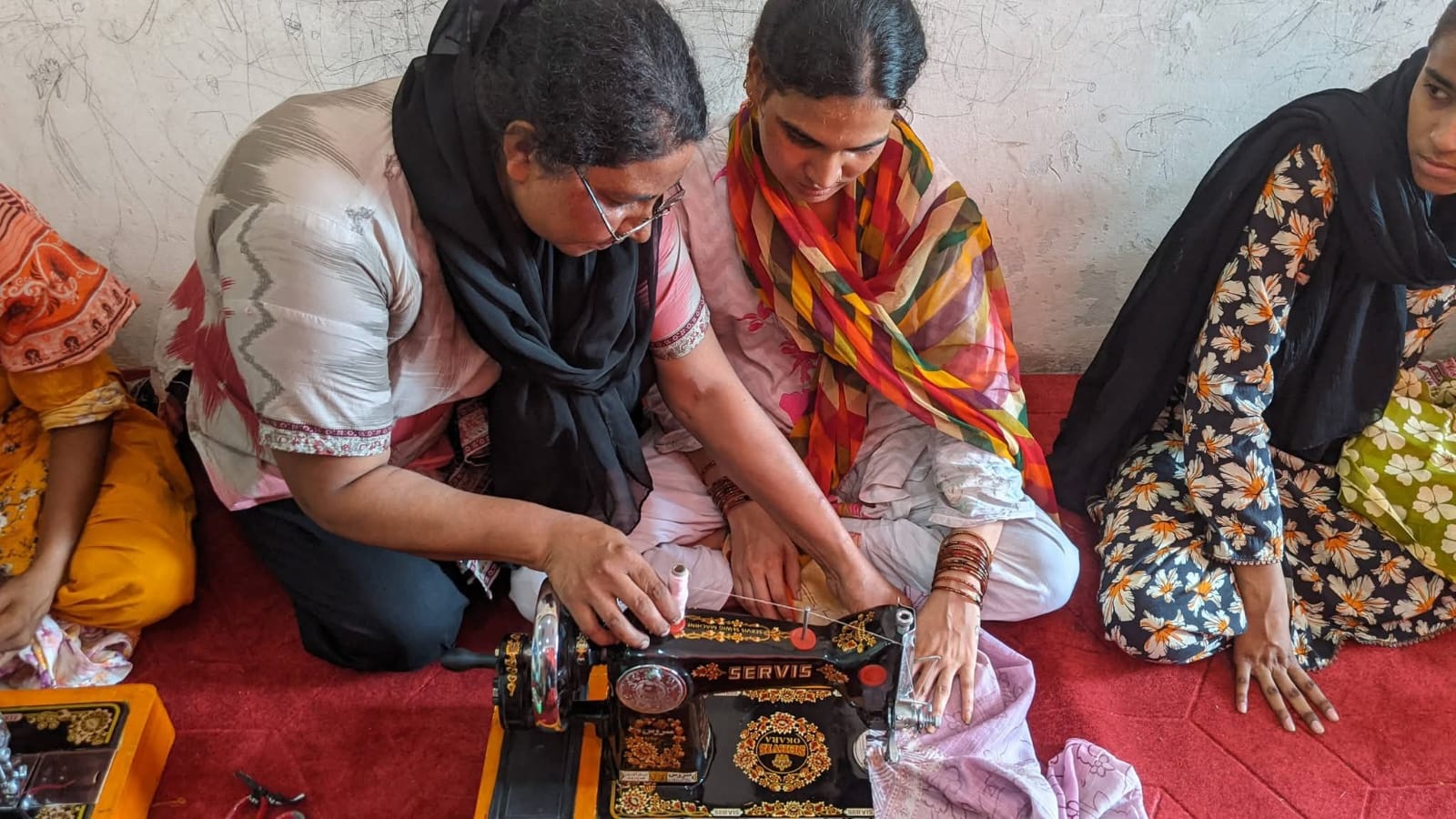 Mahnoor Shahid guiding a student's hands on a sewing machine