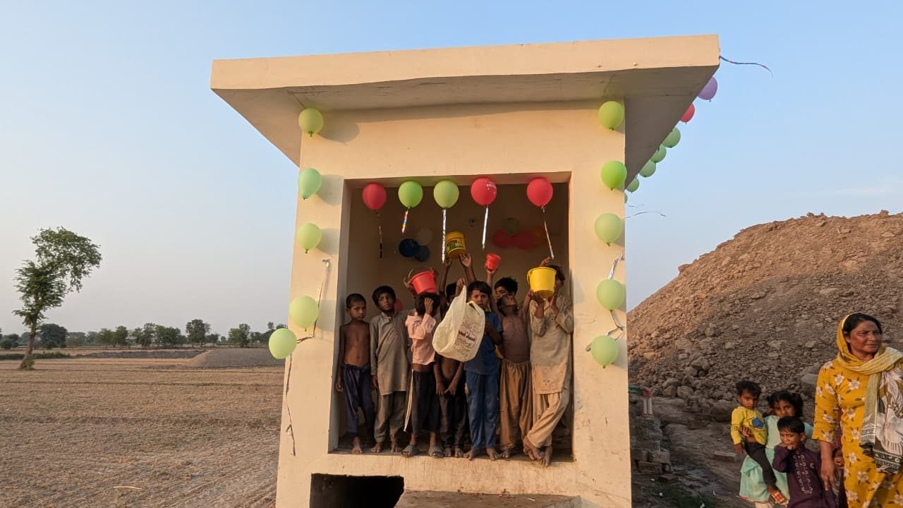 Children celebrating with balloons and water buckets at the new water station