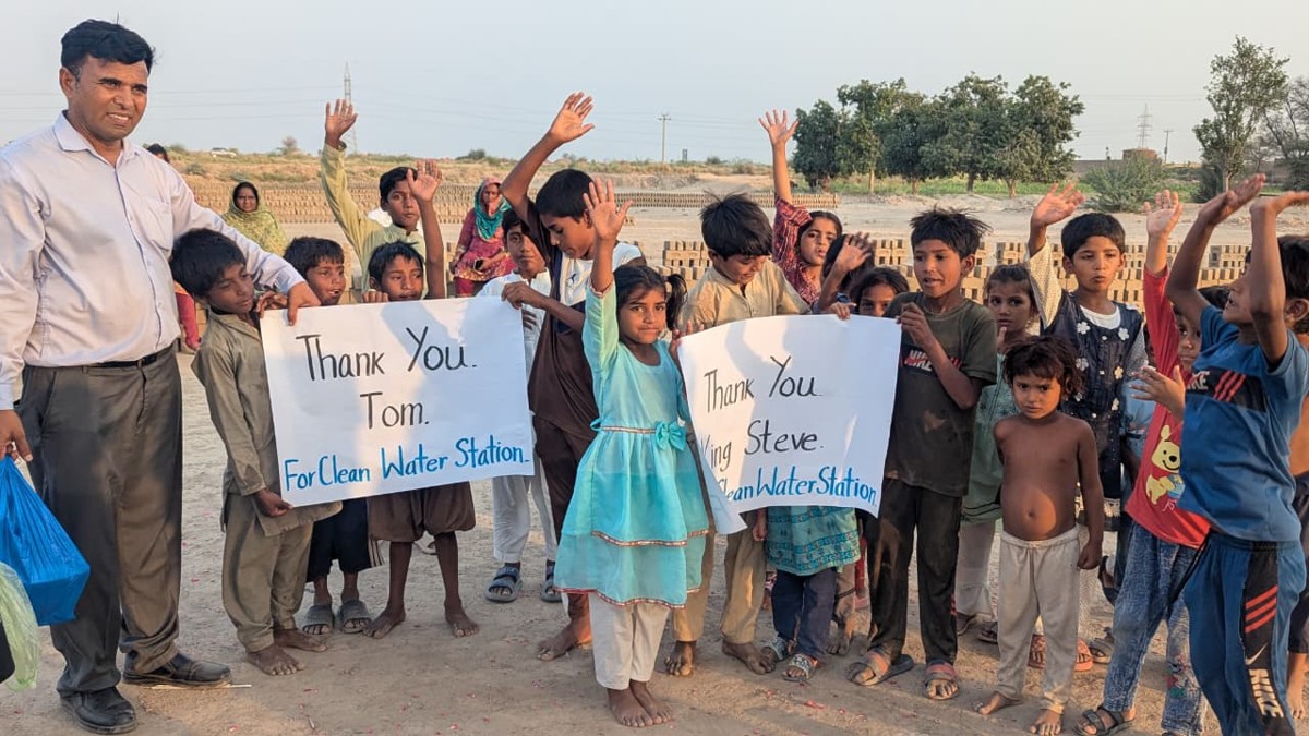 Children holding signs thanking donors for the clean water station